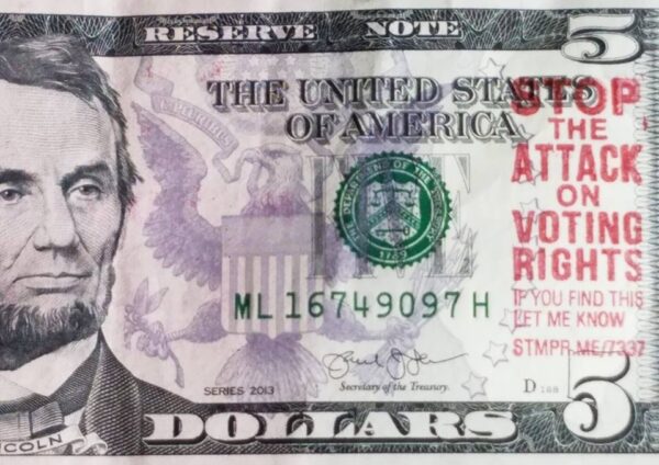 Photo of five dollar bill stamped with "Stop the attack on voting rights"